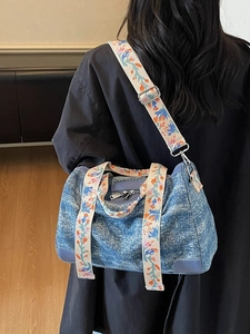 Blue denim tote bag with ethnic floral embroidered strap shown from back perspective