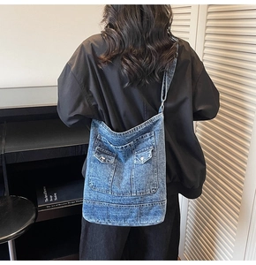 Close-up of vintage washed denim tote bag with two front pockets and wide shoulder strap
