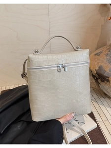 Macro view of beige crocodile embossed leather handbag with silver zip and ring pulls