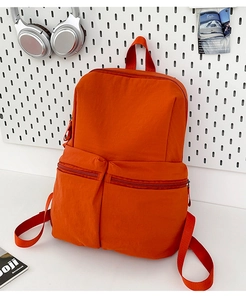 Detail view of the large capacity orange backpack with two front zipper pockets and top handle