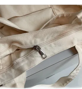 Close-up of a smooth silver zipper closure on a durable beige canvas tote bag