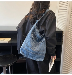 Rear view of a model wearing a large vintage washed denim tote bag with front flap pockets