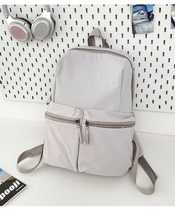 Detailed view of light gray nylon backpack with double front pockets and adjustable straps
