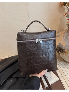 Close-up of dark brown crocodile embossed leather with silver padlock detail and metal base