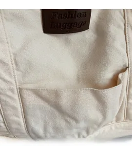 Detail of off-white canvas fabric with brown leather logo patch and external pocket seam