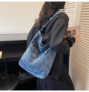 Detail of vintage washed denim tote bag showing cargo pocket and large capacity design