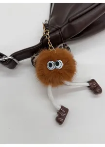 Détail d'un charm de sac en peluche marron avec de longues jambes sur un sac