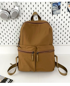 Detail view of khaki nylon backpack featuring durable double front zipper pockets and top handle