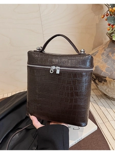 Close-up of a dark brown crocodile texture handbag with silver zippers and top handle