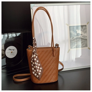 Macro detail of brown woven texture on bucket bag with elegant polka dot silk scarf