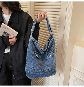 Detail of vintage washed denim tote bag with two button pockets and adjustable strap