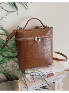 Detail of brown crocodile pattern box bag with silver metal zippers and sturdy handle