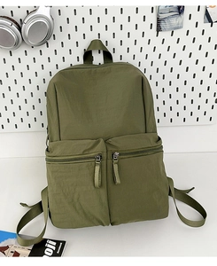 Detail of army green nylon backpack showing front zipper pockets and durable texture