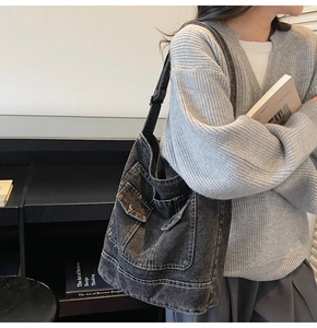 Close-up of vintage black-gray washed denim tote with multiple pockets and wide strap