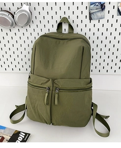 Detailed view of olive green nylon backpack with multiple zipper pockets on a white wall