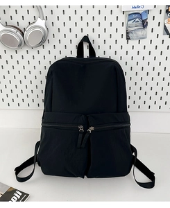 Close-up of black nylon backpack with dual zipper front pockets and adjustable straps