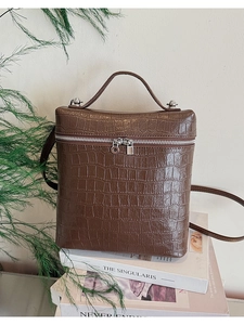 Close-up of brown crocodile texture pattern and silver zipper on women's handbag