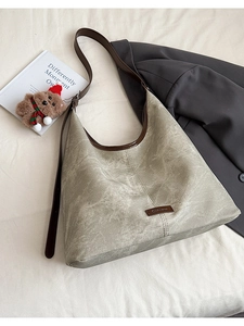 Détail d'un sac seau vintage gris-vert avec garniture en cuir brun et étiquette de logo