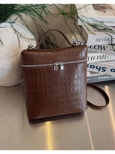 Detail of brown crocodile pattern box tote with silver zippers and elegant leather handle