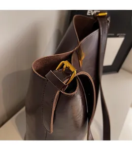 Detail view of smooth leather bucket bag featuring adjustable strap and gold metal buckles