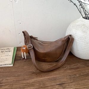 Détail d'un sac demi-lune marron avec un pendentif esthétique en forme de monstre