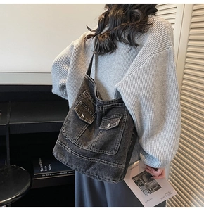 Detail of washed denim tote bag with two front flap pockets and silver metal buttons