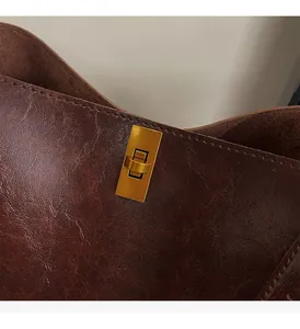 Detailed close-up of dark brown vintage leather bucket bag with gold rectangular metal twist lock