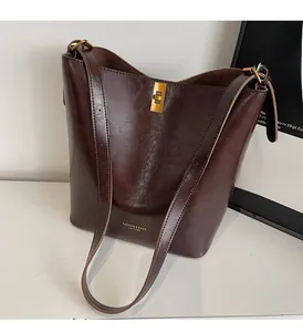 Detail of dark brown vintage bucket bag with golden buckle and fashion leather logo