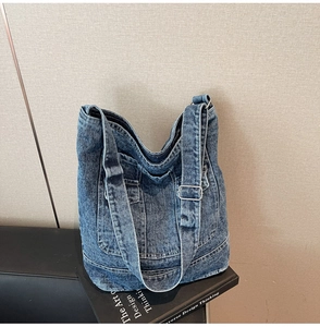 Macro shot of large washed denim tote bag with metal buckle and pocket detail