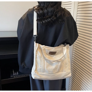 Detail of off-white canvas tote bag with adjustable shoulder strap and leather brand patch