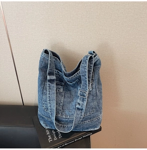 Detail of vintage washed denim tote bag featuring adjustable strap and functional pockets