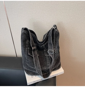 Detail of washed denim tote bag showing multiple utility pockets and adjustable buckle