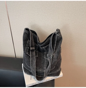 Detailed view of washed denim tote with front pockets and white contrast stitching