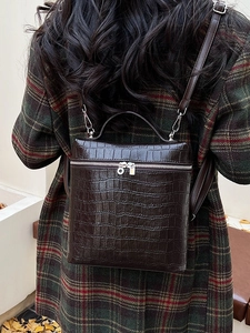 Dark brown crocodile textured backpack with top handle and adjustable shoulder straps