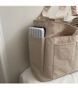 Detail einer beigen Tragetasche mit Fokus auf Seitentaschenkapazität und Knitteroptik