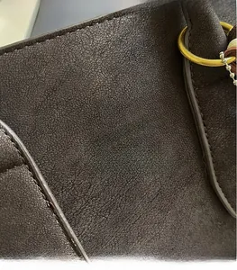 Detail of dark coffee suede bucket bag with gold ring hardware and Vanzza Hanog logo