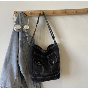 Detail of vintage washed denim tote bag featuring utility pockets and contrast stitching