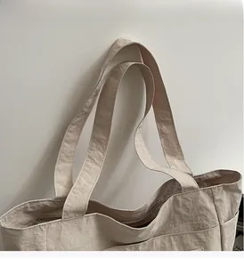 Detail der beigen Tragetasche mit verstärkten breiten Trägern und Nylon-Stoffstruktur