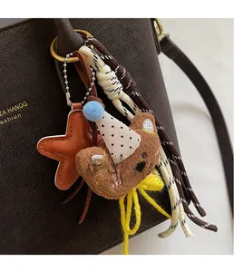 Detail of creative plush bear charm with star accessory on brown leather bucket bag