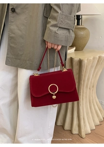 Detail of red velvet handbag with golden ring clasp and heart pendant in a chic setting