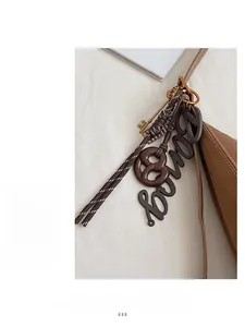 Detailed close-up of a brown leather bag featuring stylish charms and a metal key pin