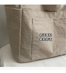 Detail der beigefarbenen Canvas-Tasche mit weißen Nähten und weicher Stoffstruktur