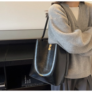 Close-up of black glossy leather bucket bag with gold lettering and metallic hardware