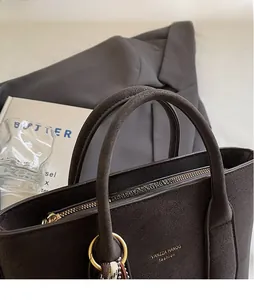 Detail of dark brown suede bucket bag with gold lettering and decorative silk scarf