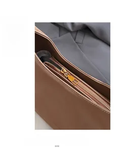 Detailed macro view of high-quality gold metal zipper and stitching on brown tote bag