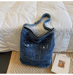 Macro view of washed denim hobo bag featuring metal button pockets and adjustable strap