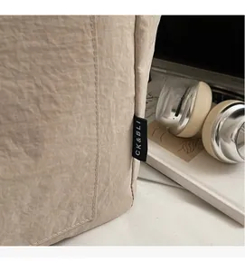 Detail der beigen Tragetasche aus Knitterstoff mit CK & BLI Markenetikett und sauberer Naht