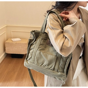 Detail of army green canvas tote bag with adjustable strap and side pockets for commuting