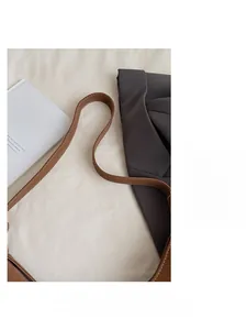 Detail of a brown leather shoulder strap with white contrast stitching on a tote bag
