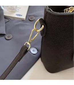 Close-up of golden metal hook on dark brown suede handbag with high-quality texture